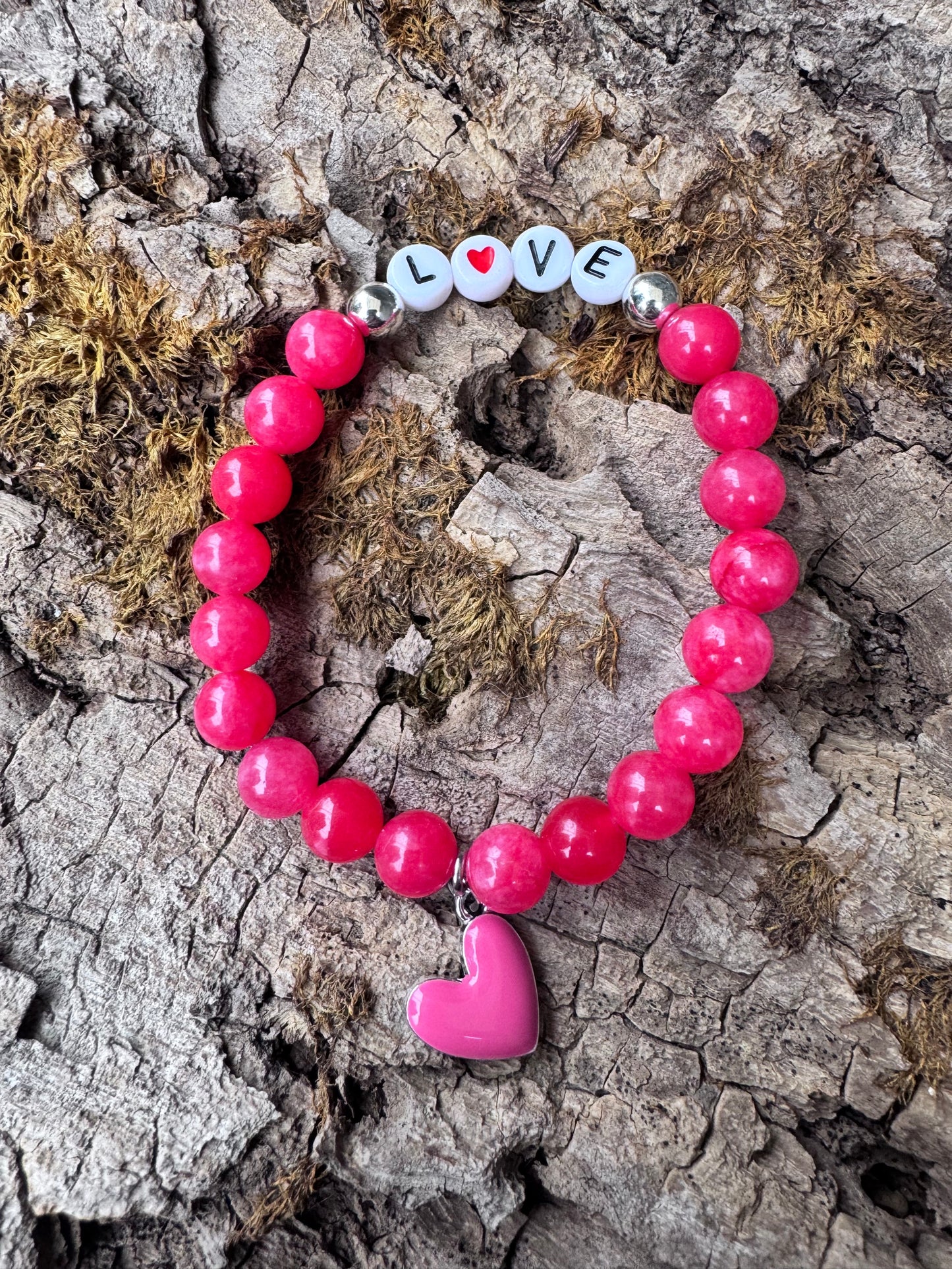 Ein pinkes Perlenarmband mit dem Wort Love und einem pinken Herzanhänger