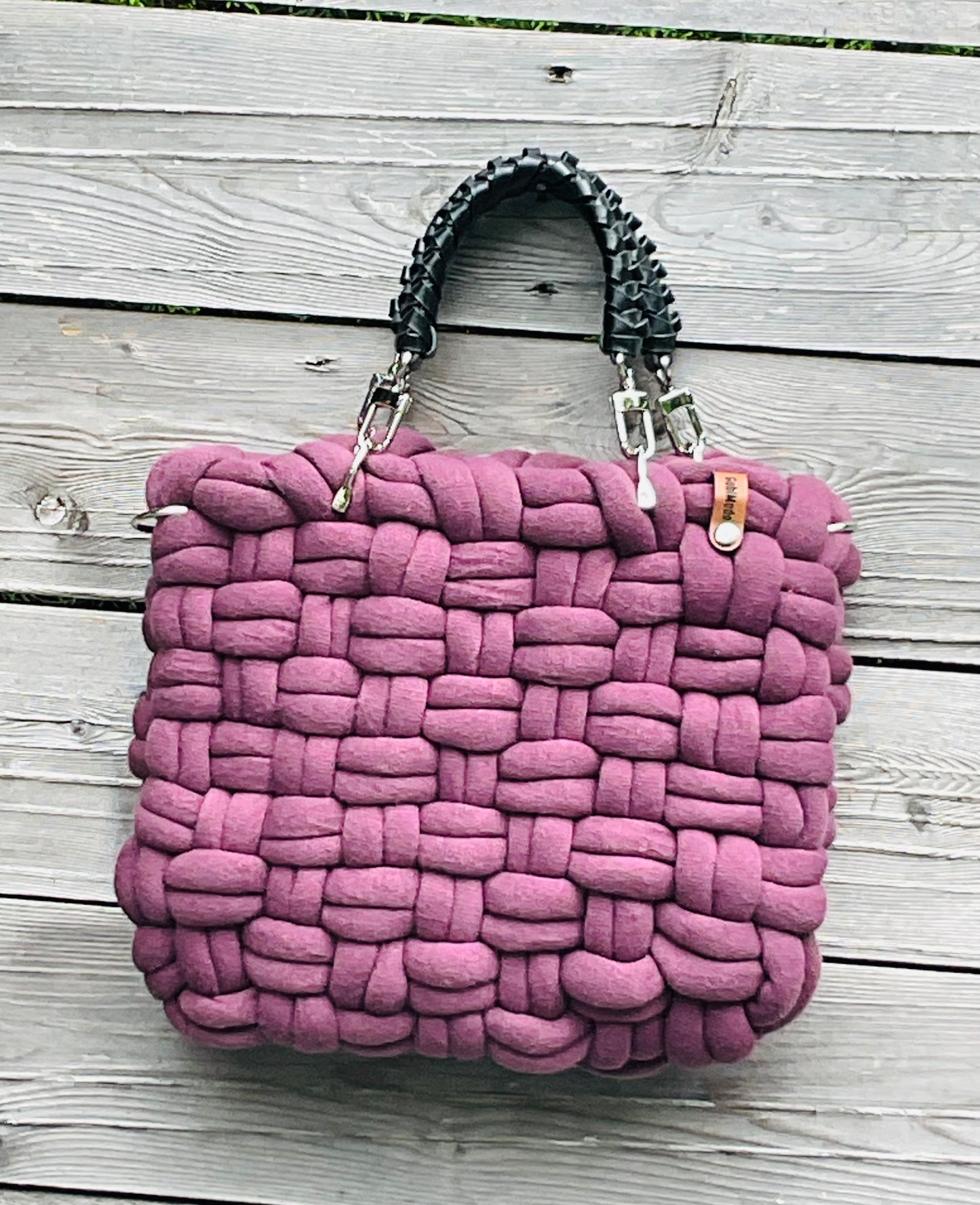 Eine geflochtene Tasche in Plum mit schwarzen Ledergriffen