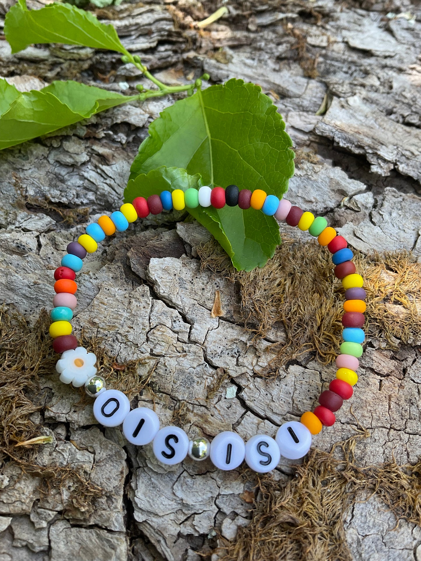 Ein Armband aus bunten Perlen mit dem Wort Ois Isi mit einer Blumenperle