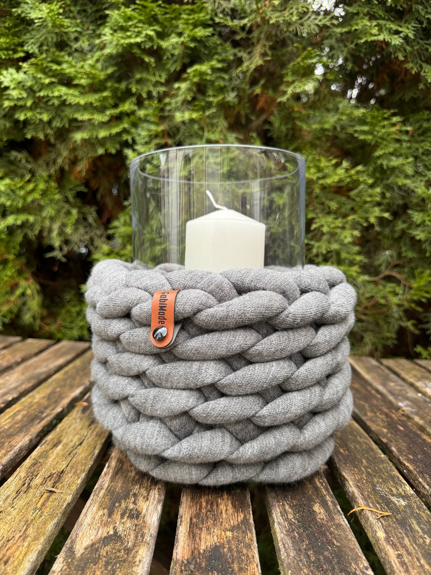 Ein großes graues gesticktes Windlicht mit Glaszylinder und Kerze.