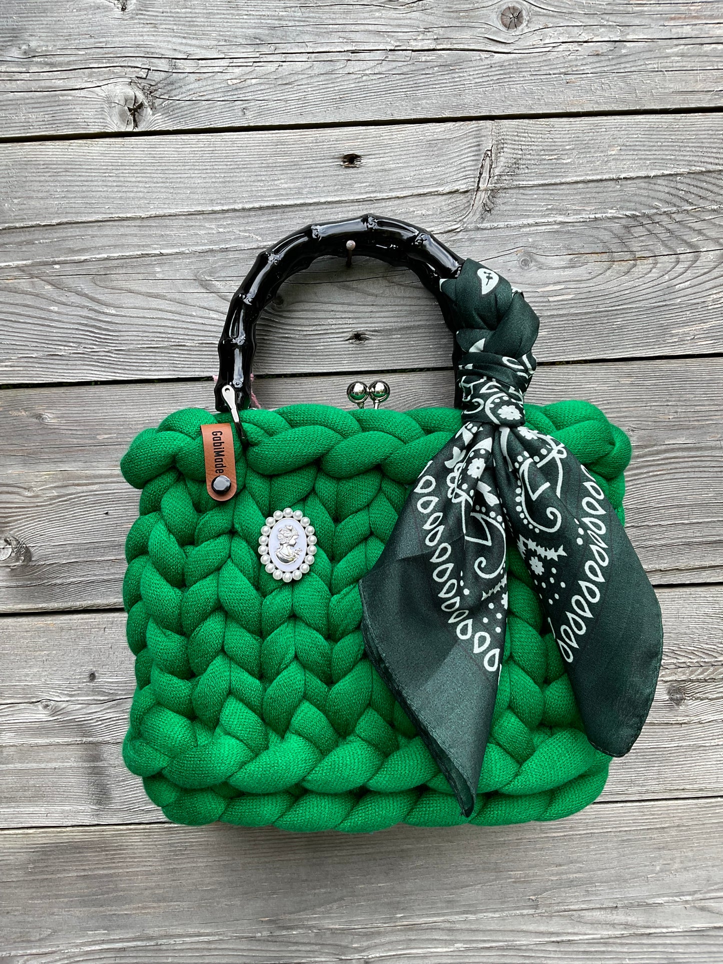 Eine grüne gestrickte Trachtentaschen mit schwarzen Griffen