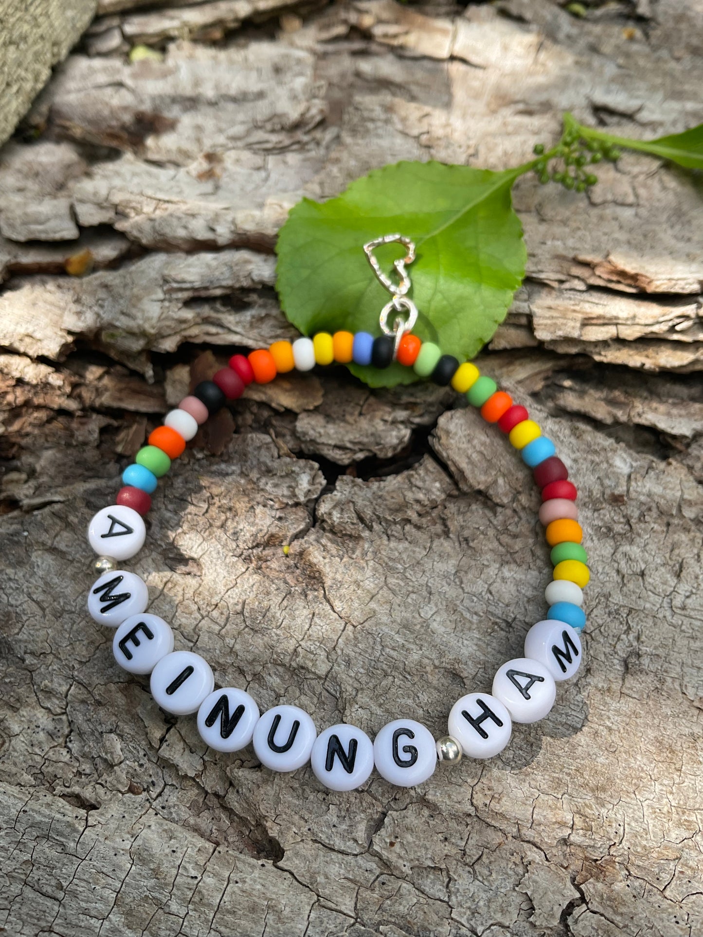 Ein Armband aus bunte Perlen mit den Worten A Meinung Ham mit einem silbernen Herzanhänger