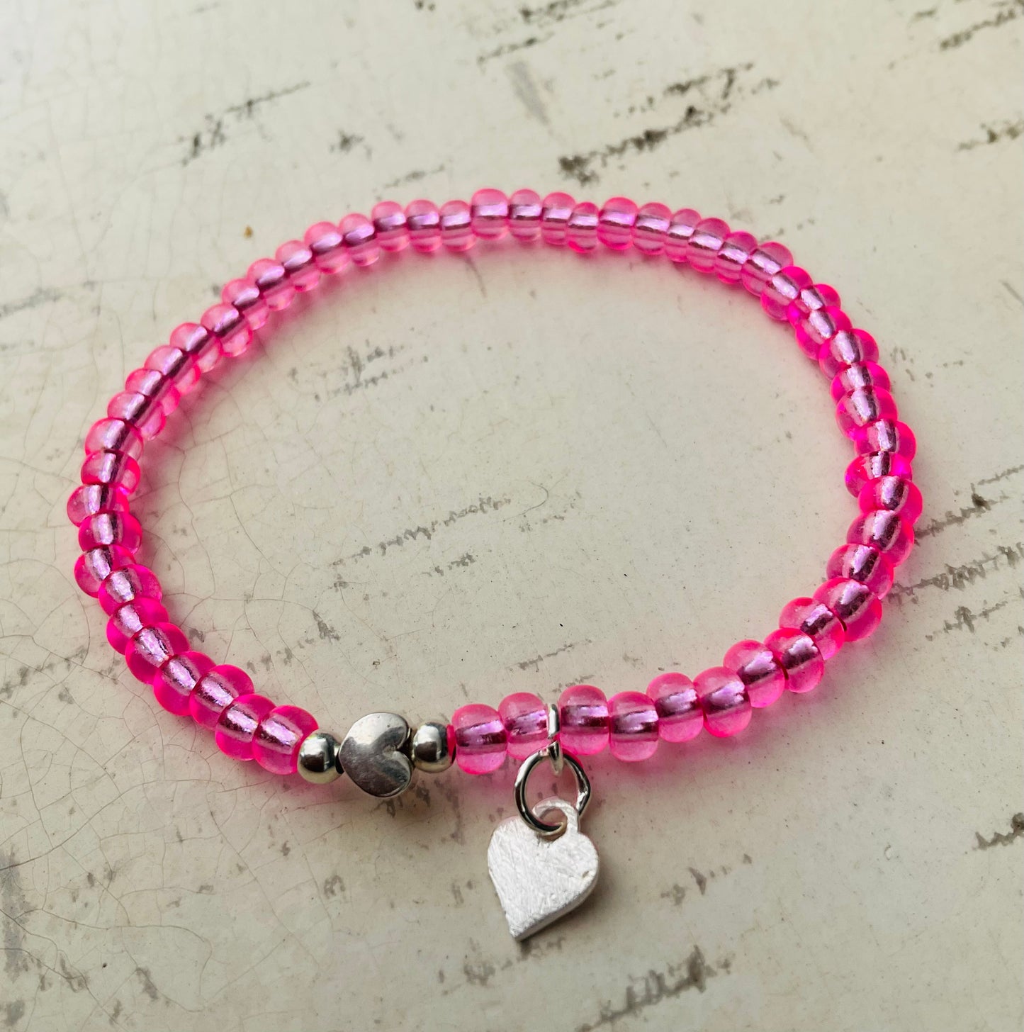 Ein pinkes Perlenarmband mit Herzanhänger