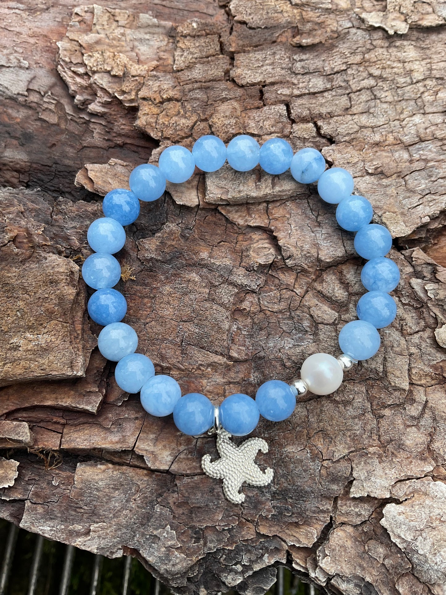 Ein hellblaues Armband mir einer Perle und einem silbernen Seestern Anhänger