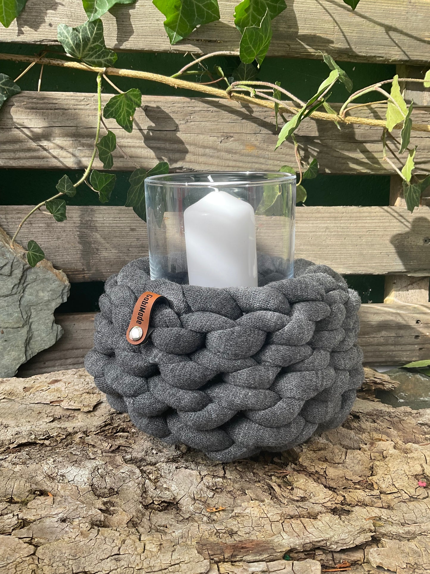 Ein gestricktes anthrazitfarbenes Windlicht mit Glaseinsatz