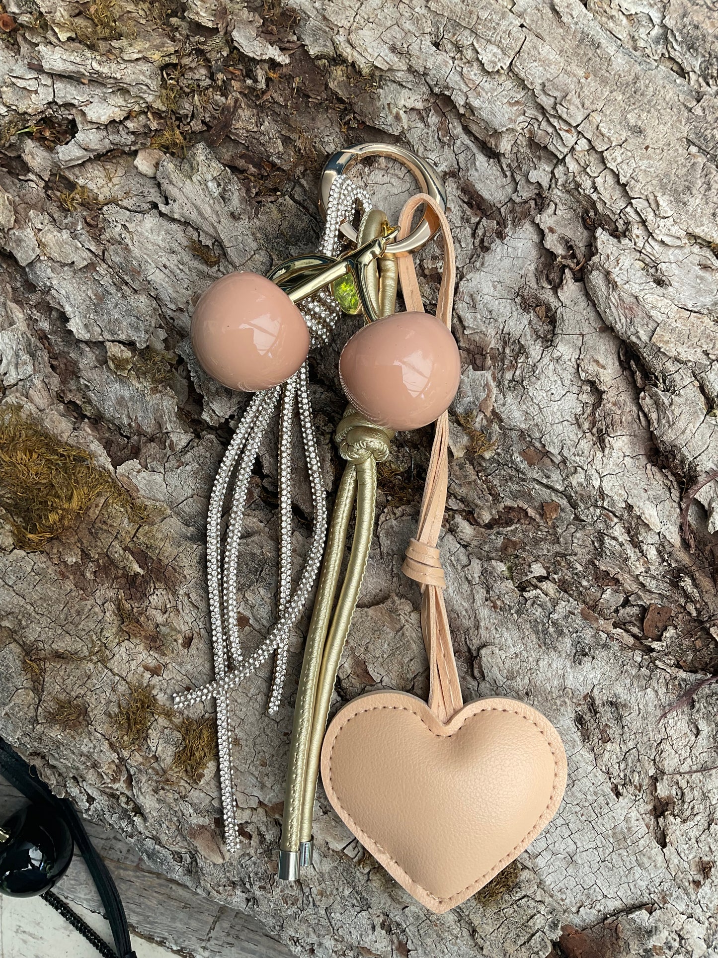Ein Taschenanhänger in Beige und Gold mit Herz und Kirschen