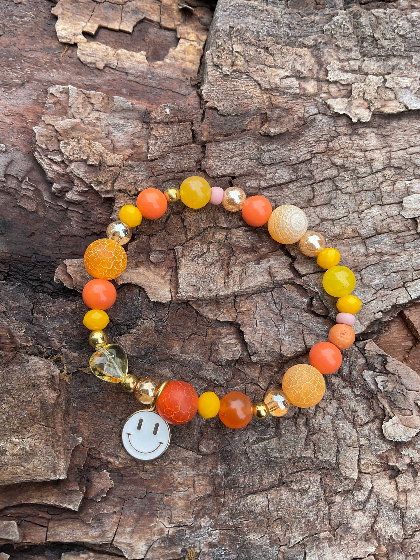 Ein oranges Perlenarmband mit einem weißen Smiley Anhänger