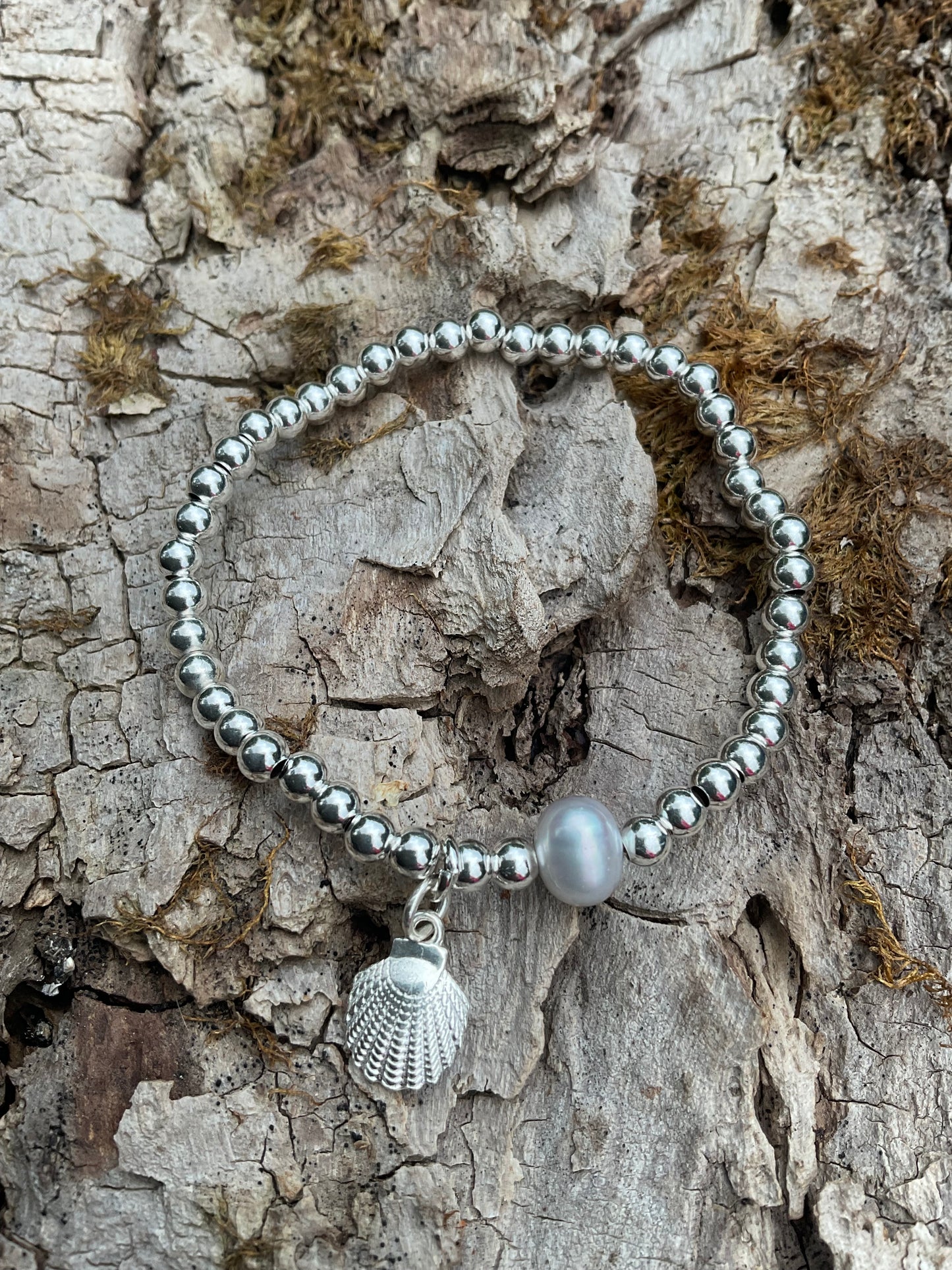 Ein 925 Silber Perlenarmband mi einer Perle und einem Muschelanhänger.