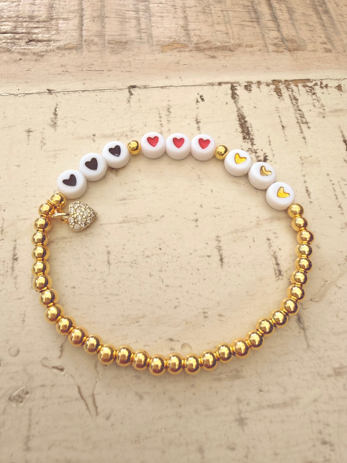 Ein goldenes perlenarmband mit Herzanhänger