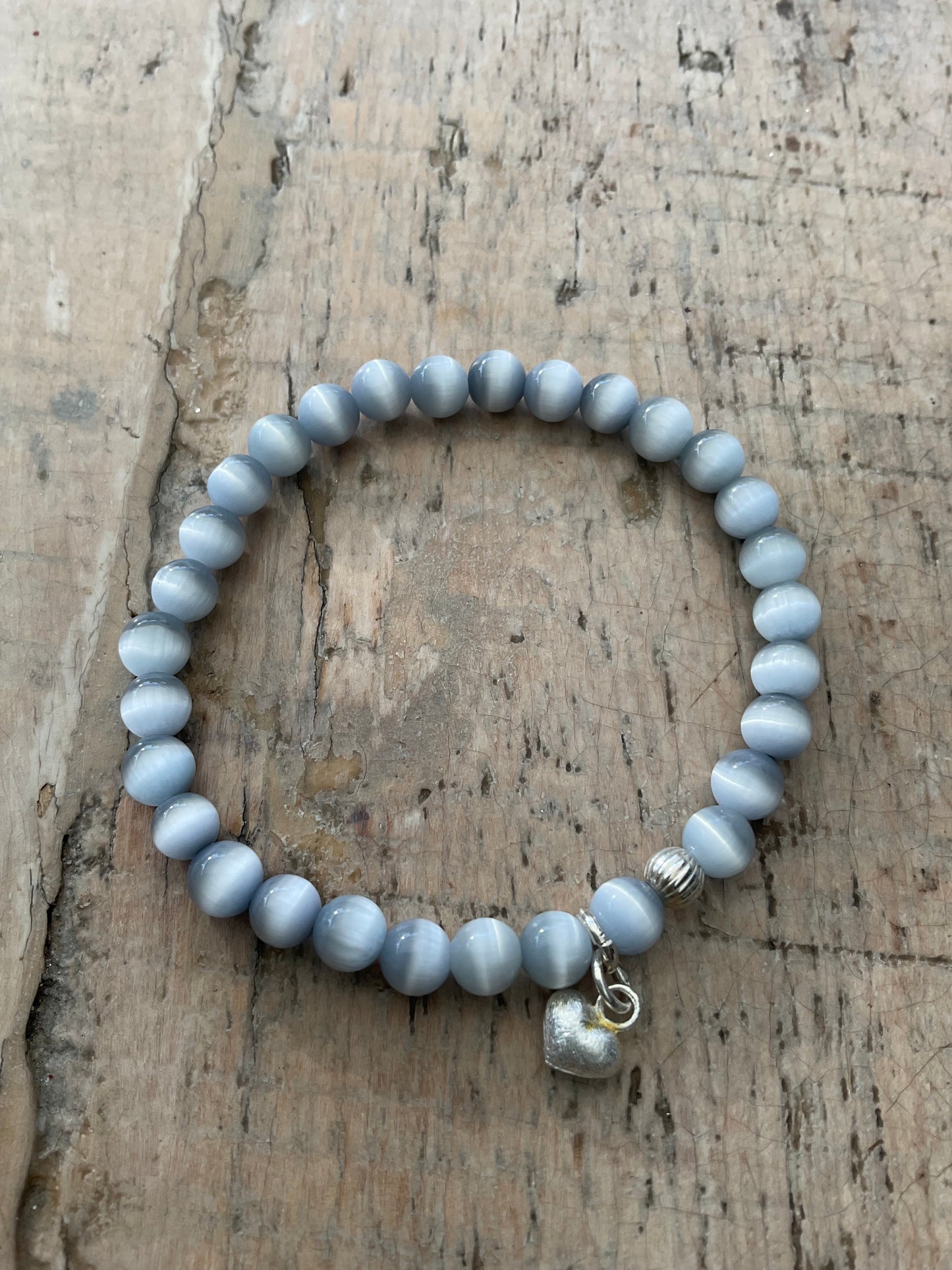 Ein graues perlenarmband mit Herzanhänger