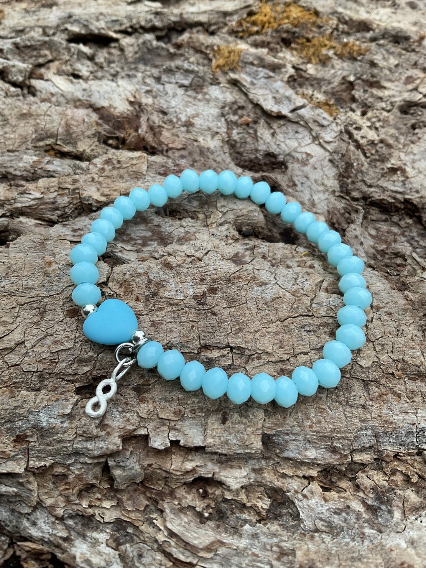 Ein blaues Armband mit einer Herzperle und einem silbernen Unendlichkeits Anhänger