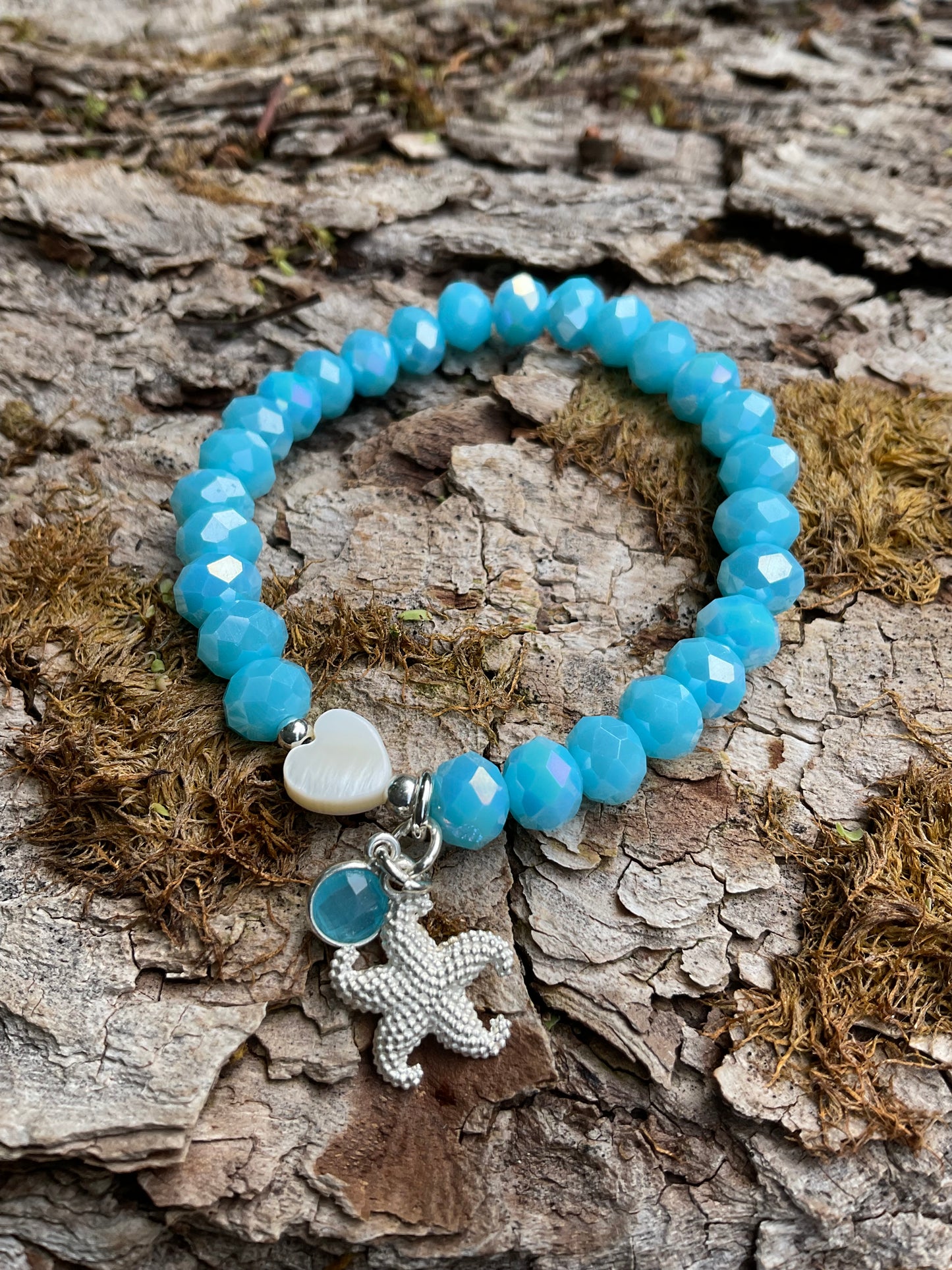 Ein blaues Armband mit einem Herz und einem silbernen Seestern Anhänger