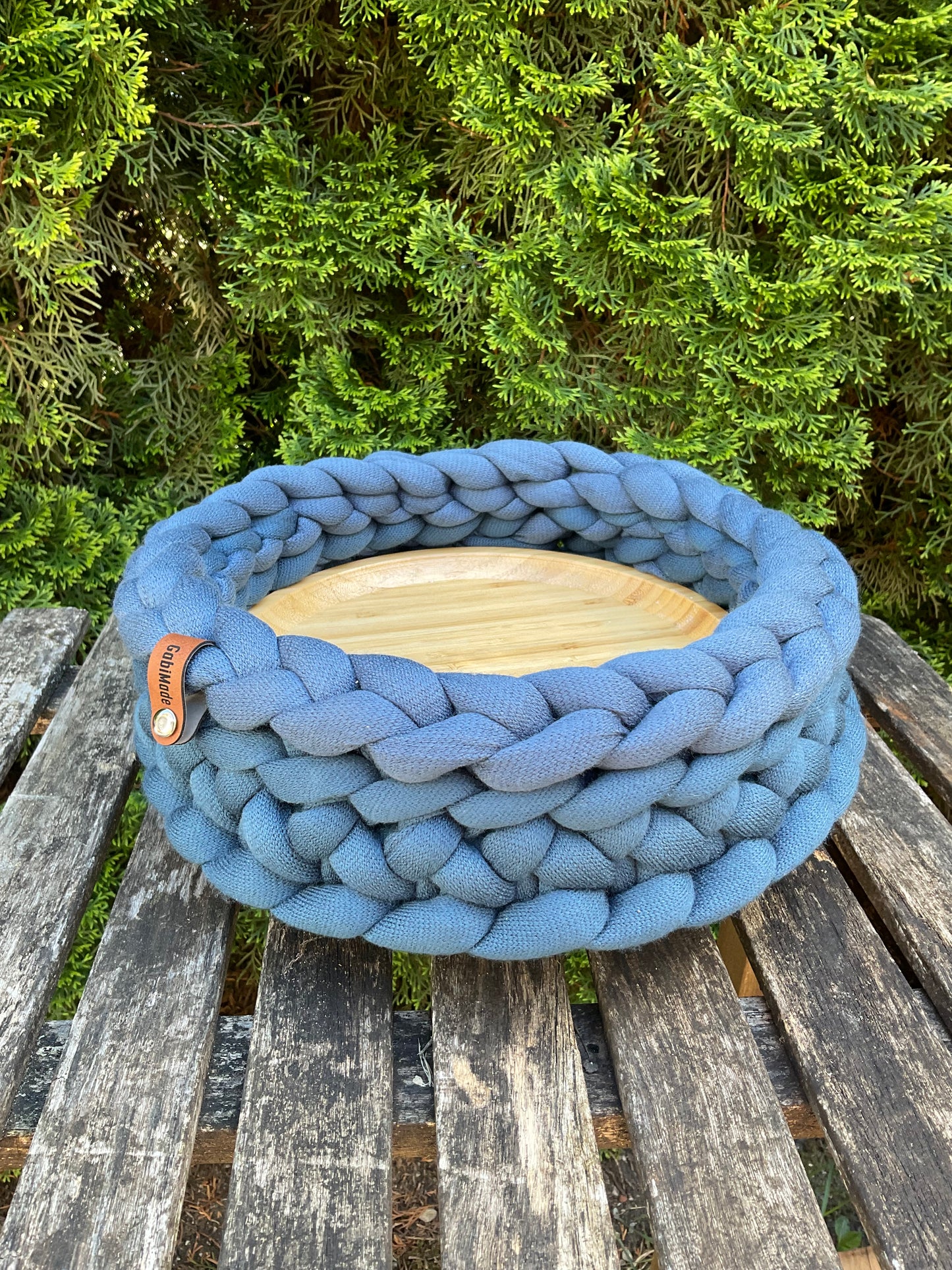En gestricktes Tablett in Jeansblau mit Holzteller in Medum.