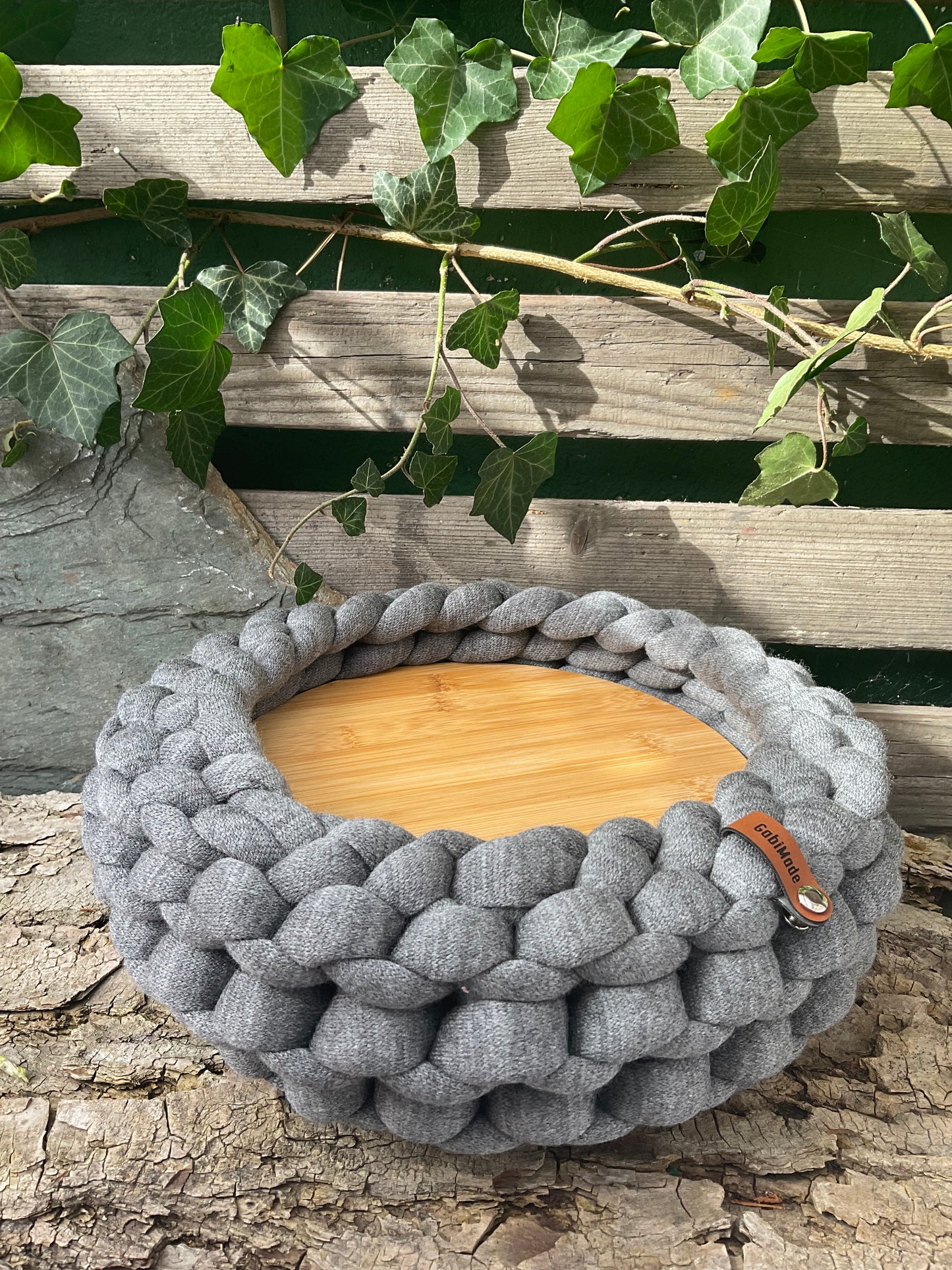 Ein gestricktes graues Tablett mit Holzteller