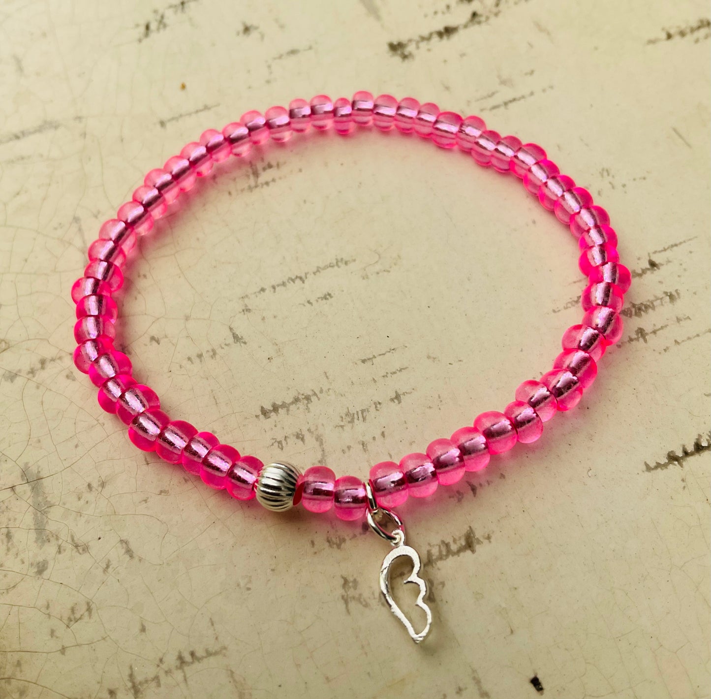 Ein pinkes Perlenarmband mit Flügelanhänger