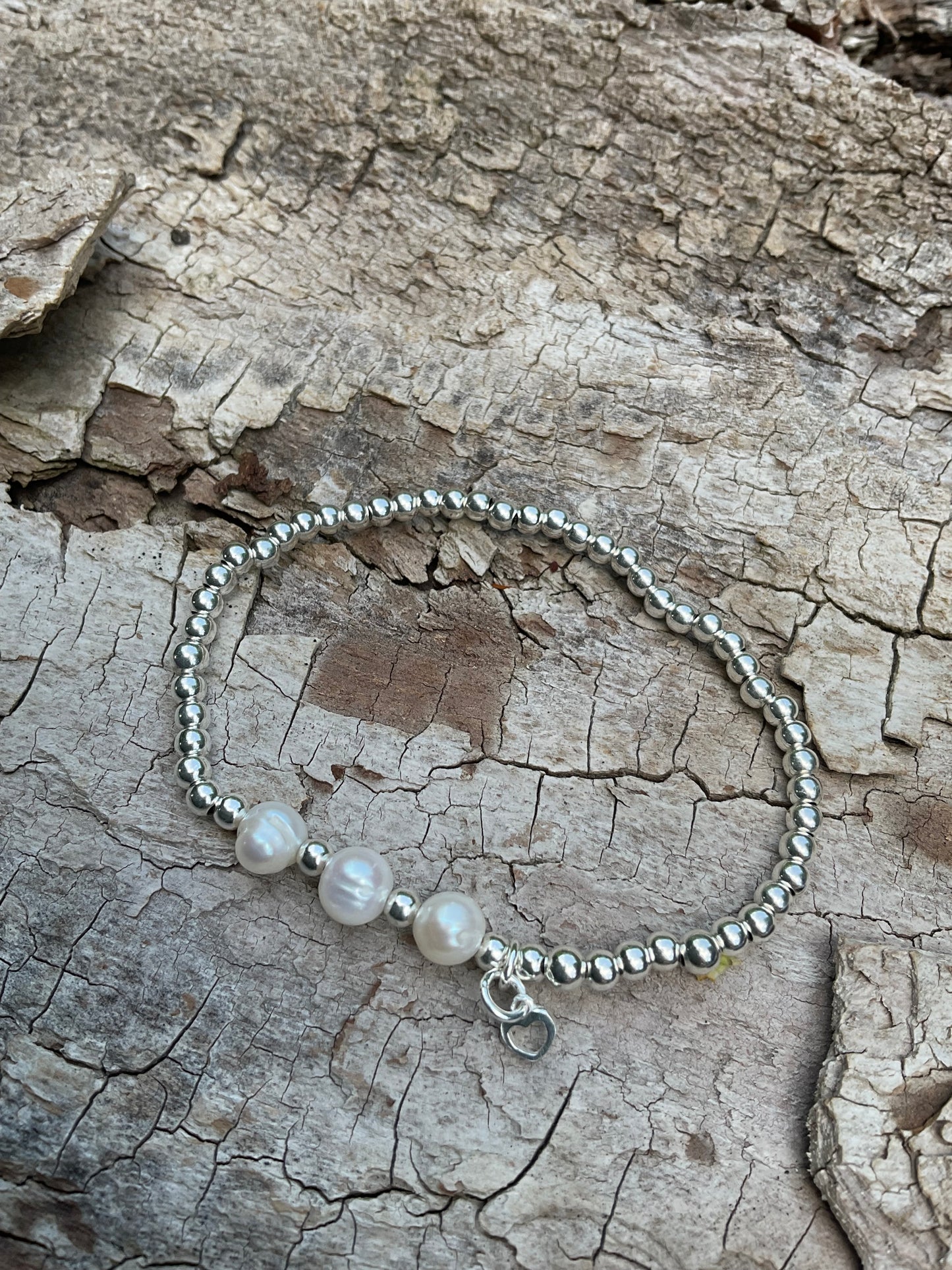 Ein Armband aus Silberperlen und Perlen mit Herzanhänger