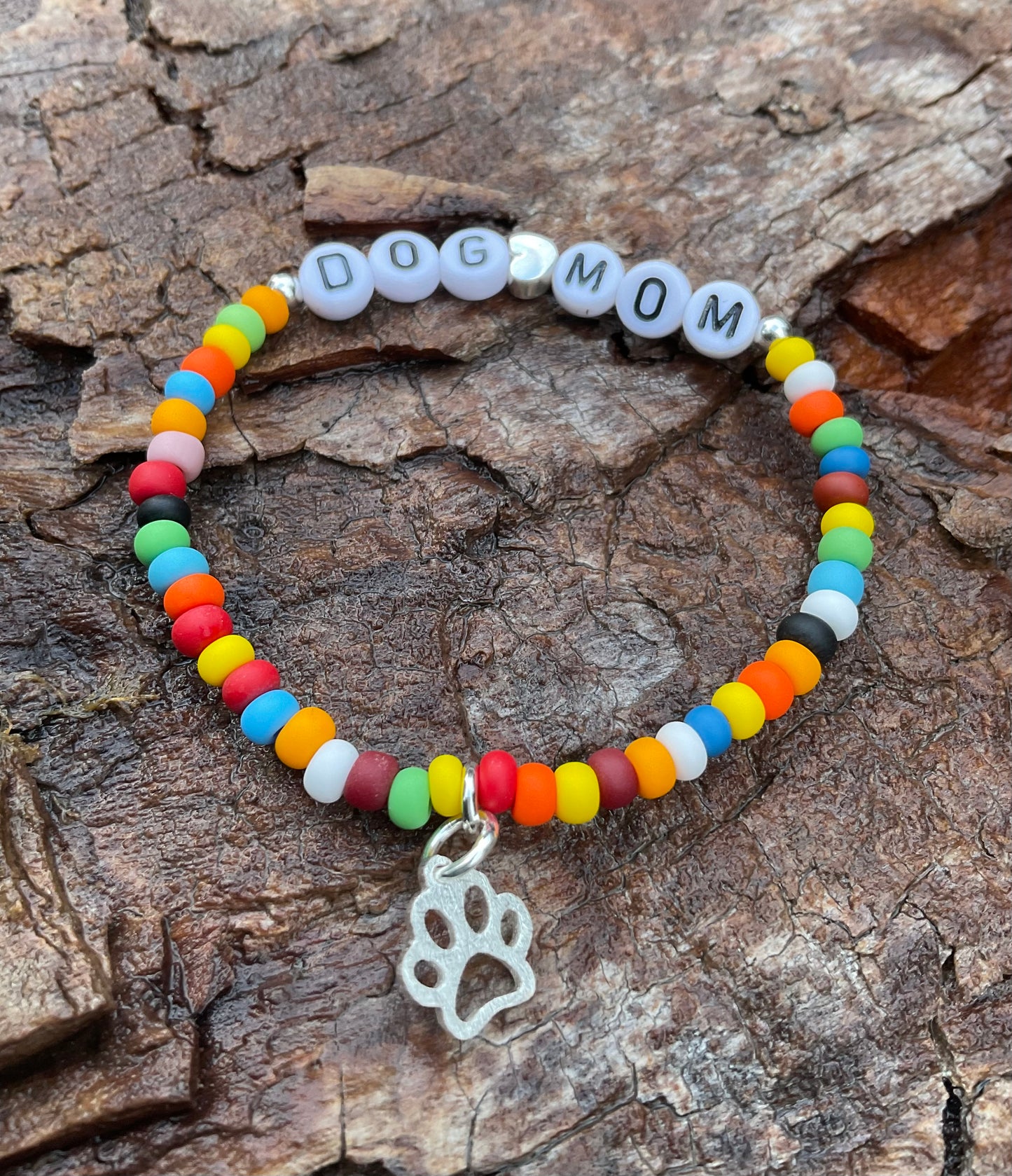 Ein buntes Armband mit den Worten Dog Mum und einem silbernen hundepfoten Anhänger