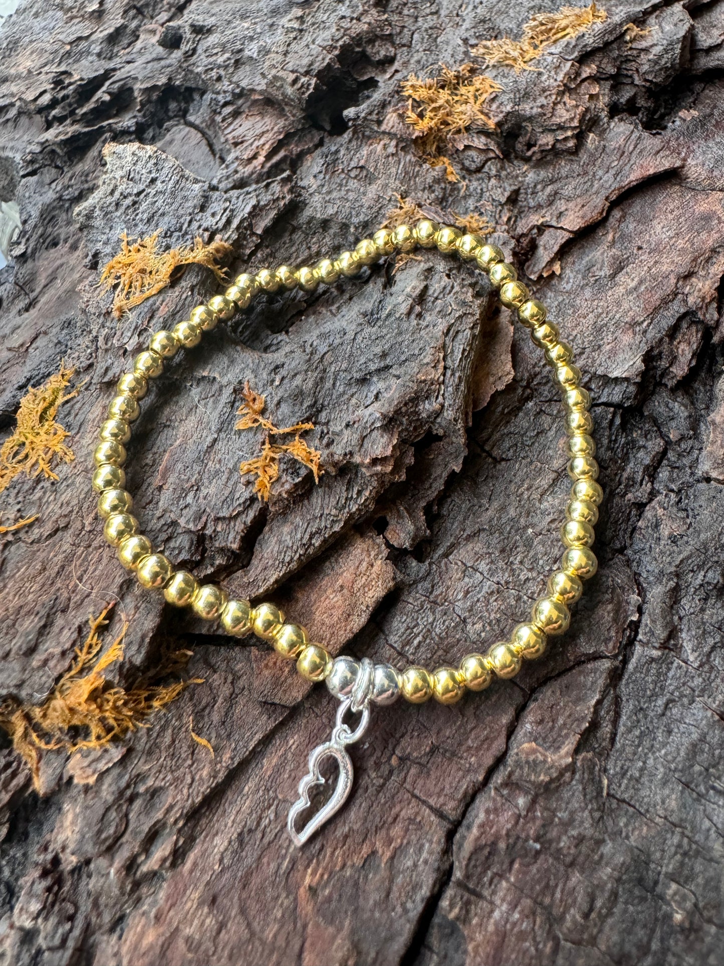 Ein vergoldetes Perlenarmband mir einem Silber Flügelanhänger.