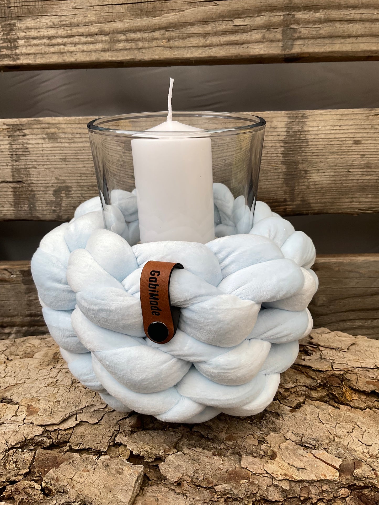 Ein gestricktes hellblaues Windlicht mit Glaseinsatz