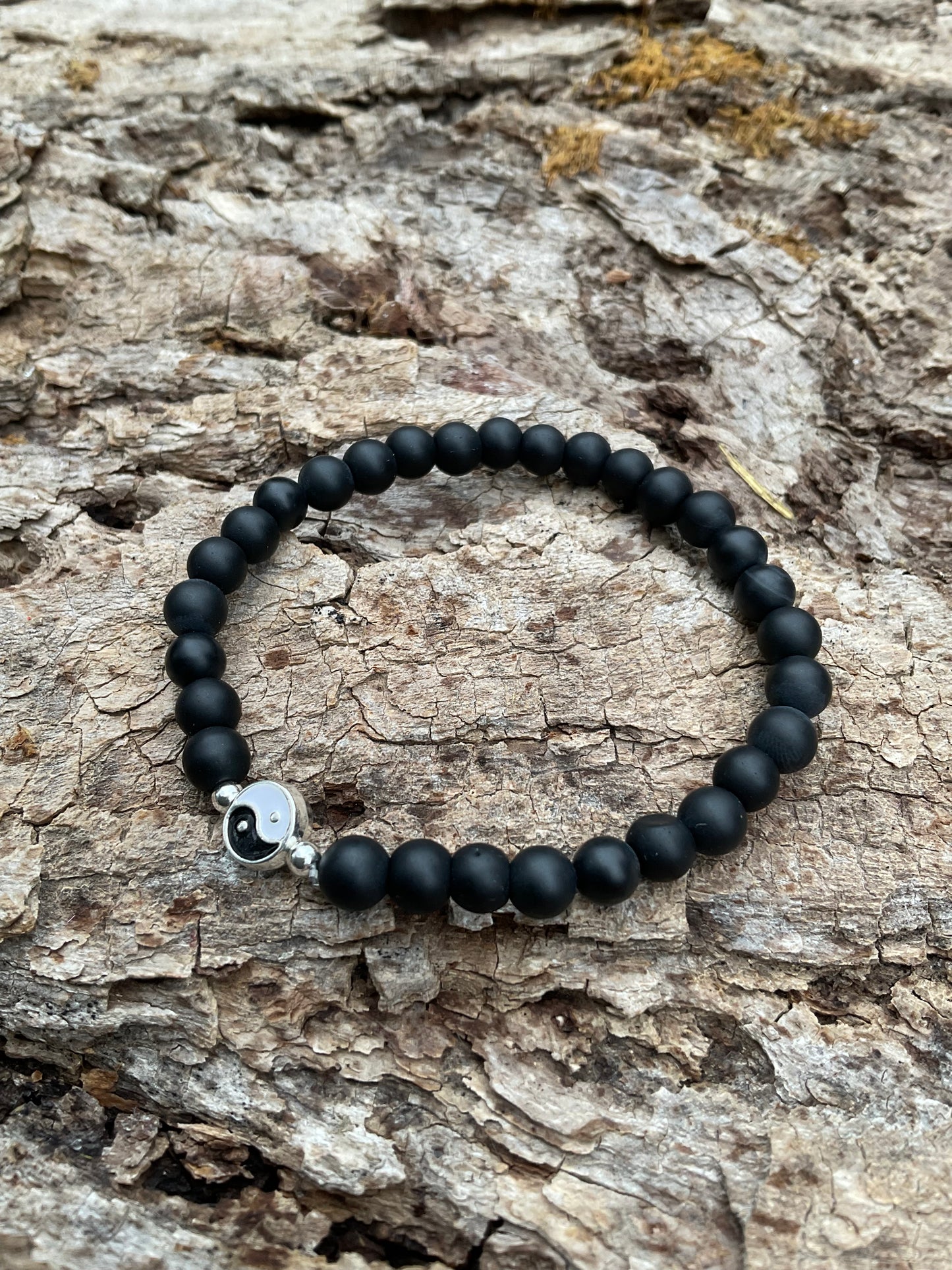 Ein schwarzes Armband mit einer YINGYANG Perle