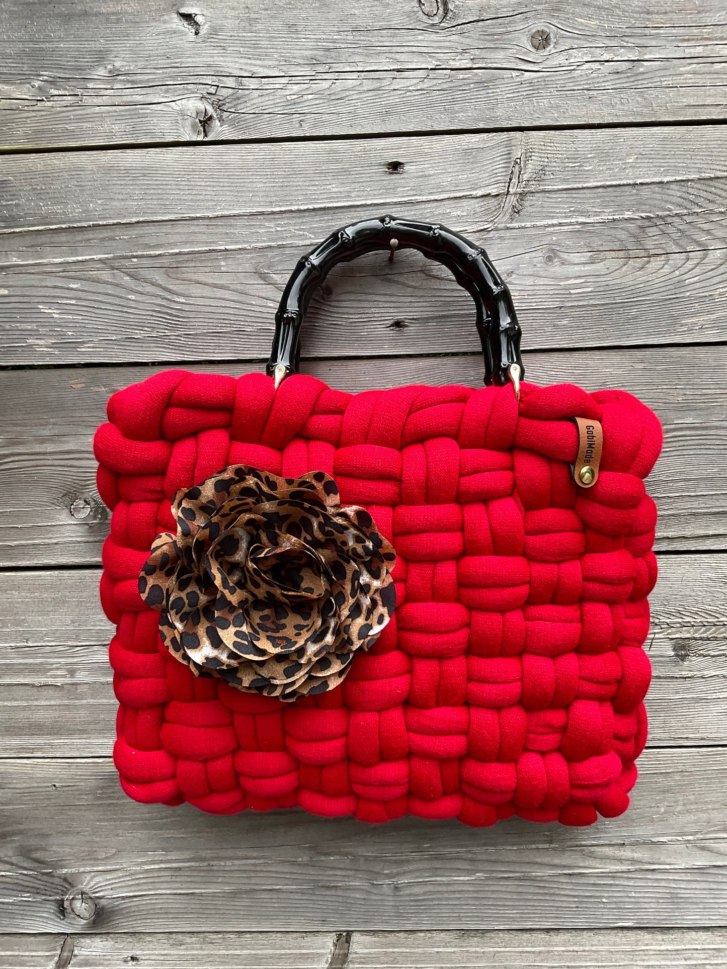 Eine rote gestrickte Tasche mit Blumenbrosche