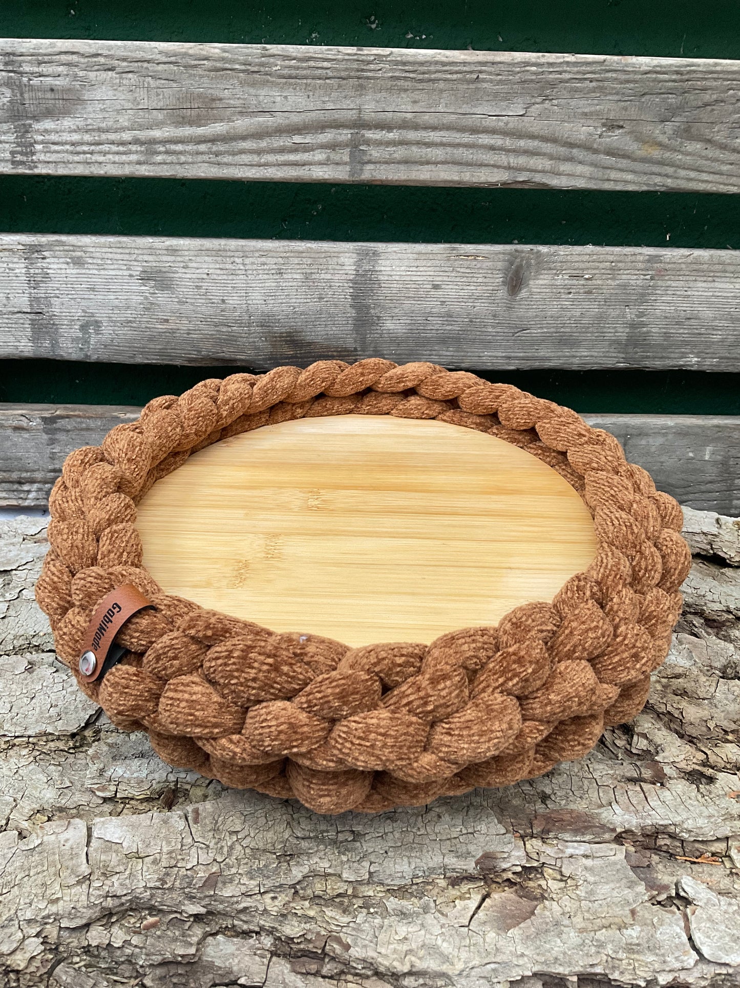 Ein gestricktes braunes Tablett mit Holzteller