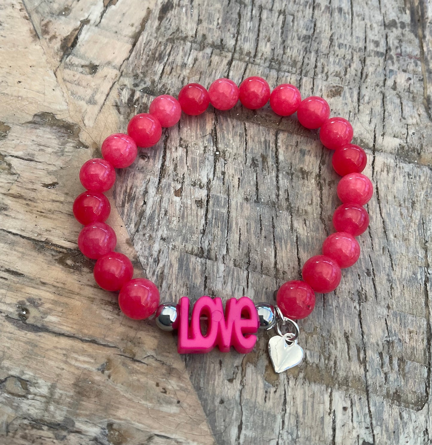 Ein pinkes Perlenarmband mit love und Herzanhänger