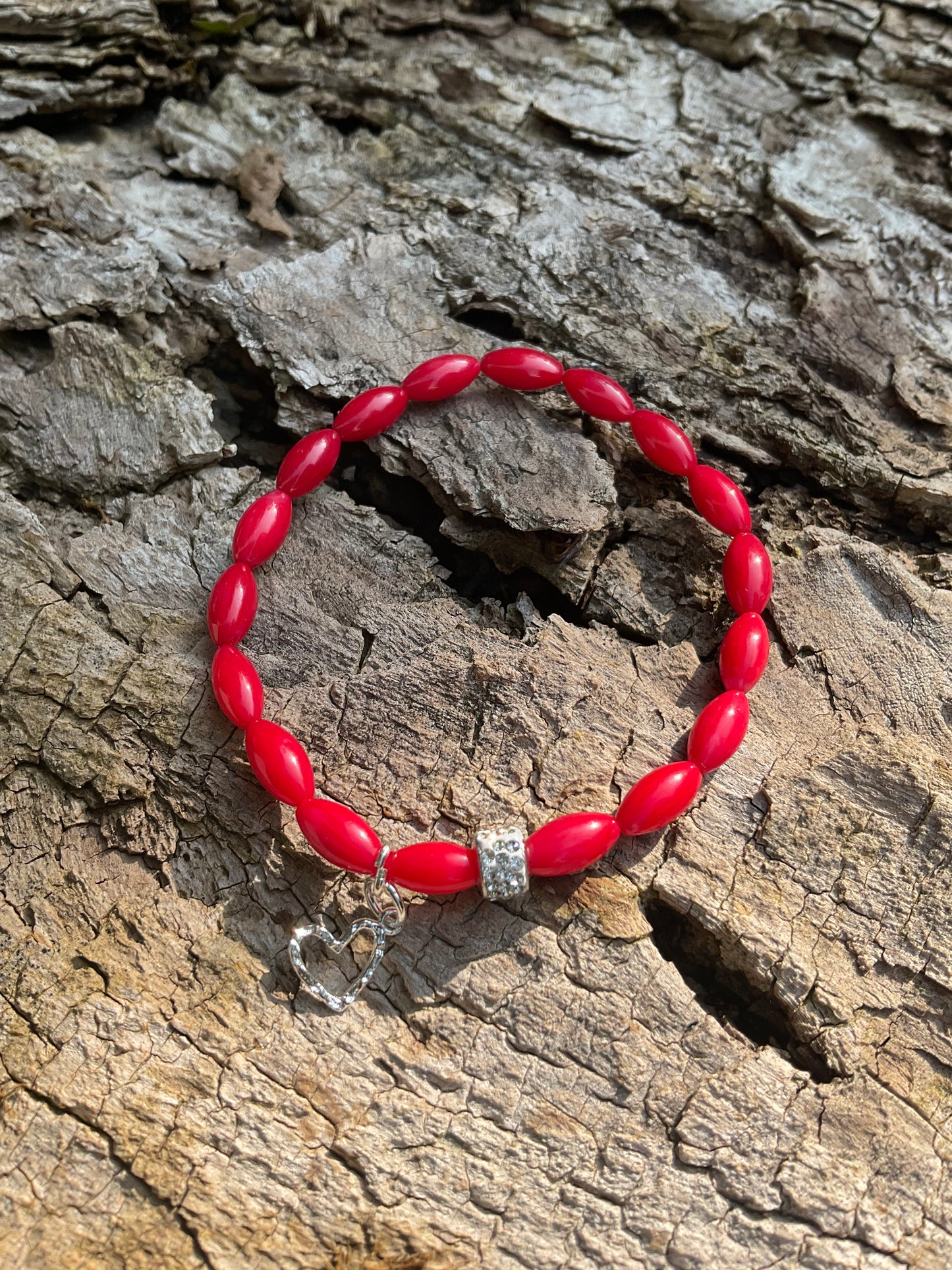 Ein rotes Perlenarmband mit Herz Anhänger