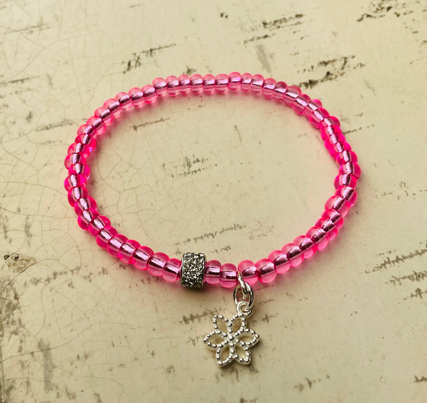 Ein pinkes Perlenarmband mit Blumenanhänger