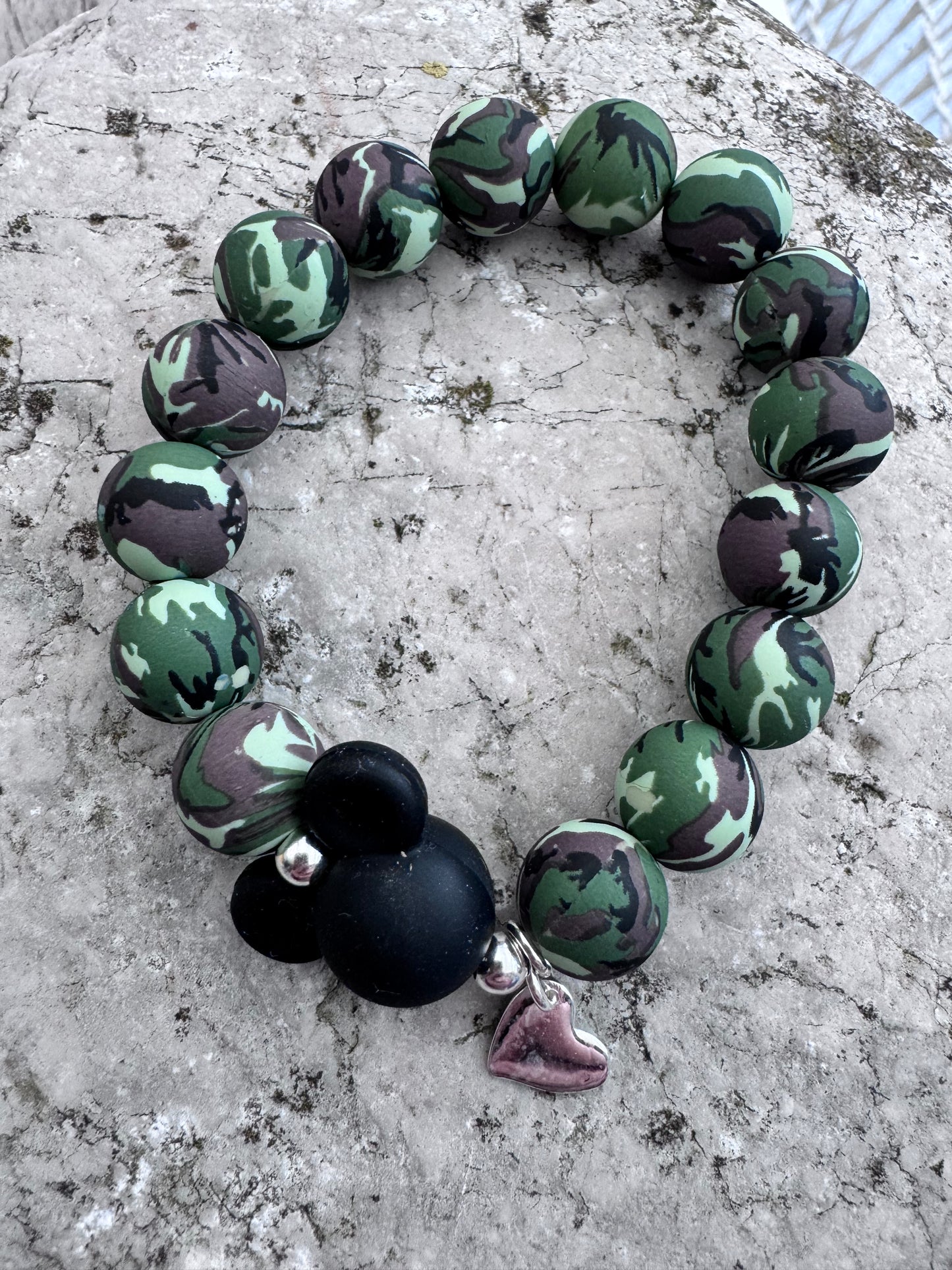 Ein Armband aus Camouflage Silikonerlen, einer Silikon MIckey Maus und einem Herzanhänger.