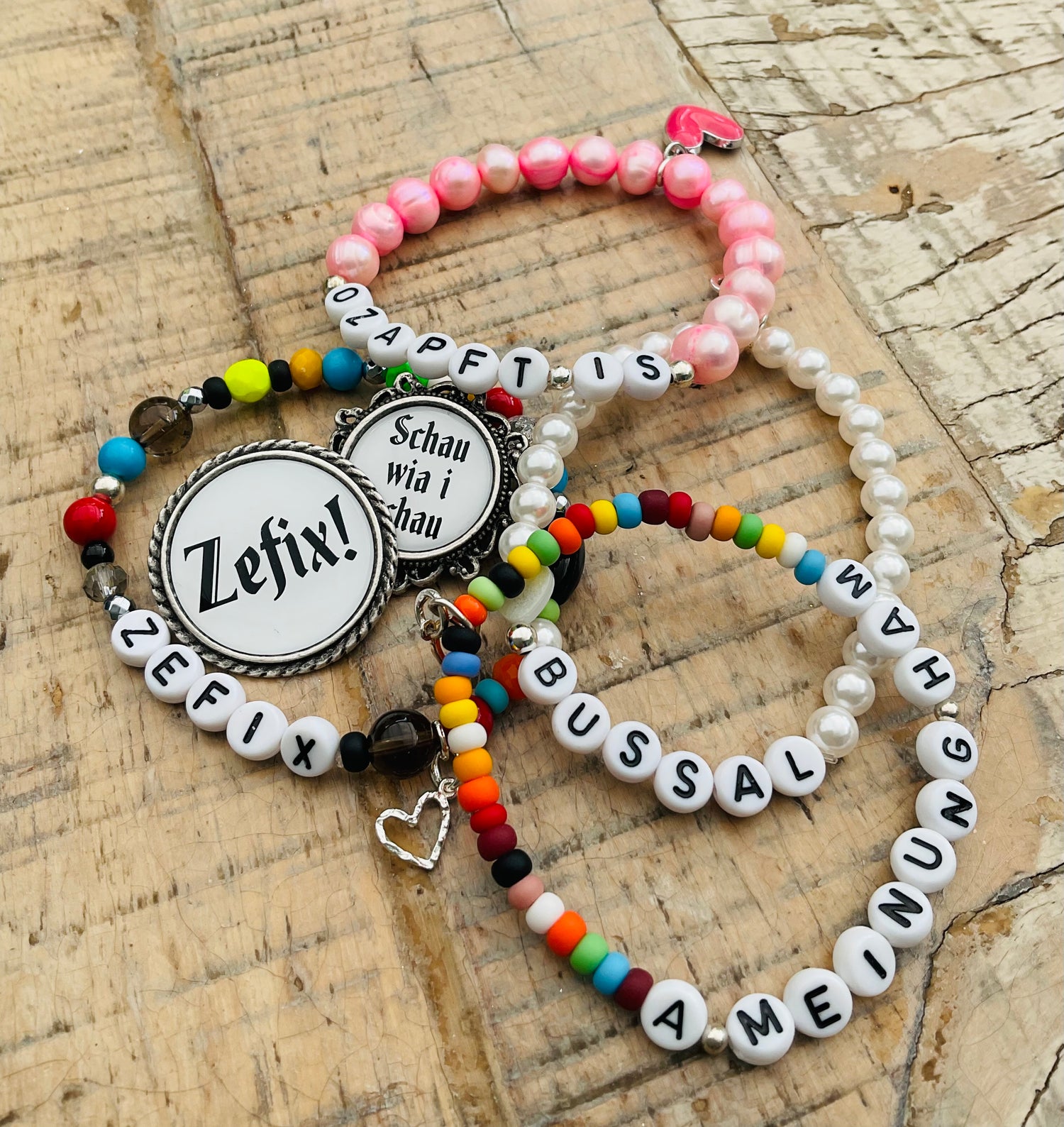 Verschiedene bunte Armbänder mit verschiedenen Worten und Anhängern stilvoll angeordnet.