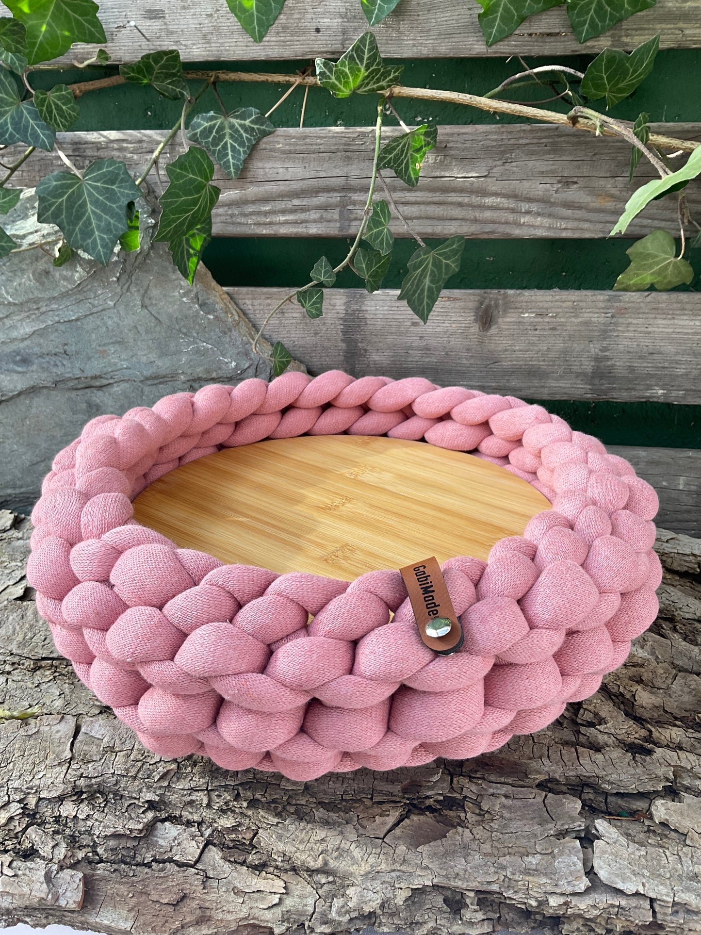 Ein gestricktes rosa Tablett mit Holzteller