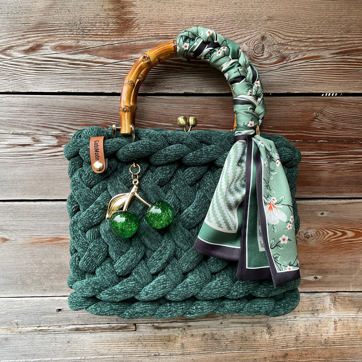 Eine gestrickte grüne Trachtentasche mit Brosche und Bambusgriffen 