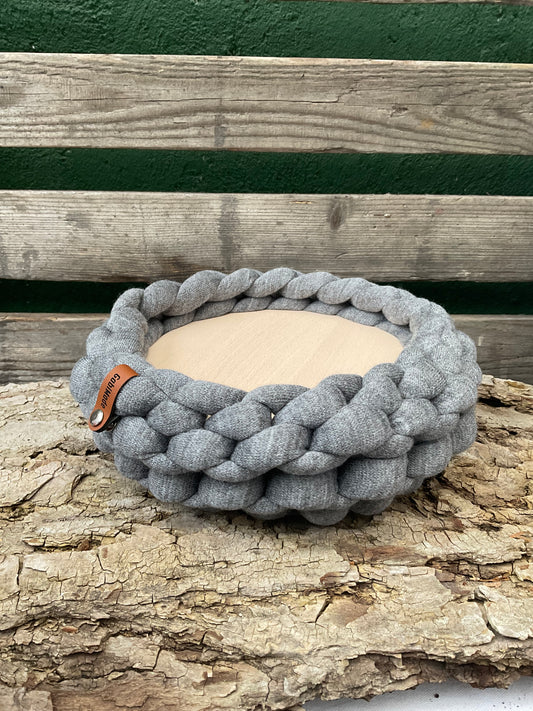 Ein gestricktes graues Tablett mit Holzteller