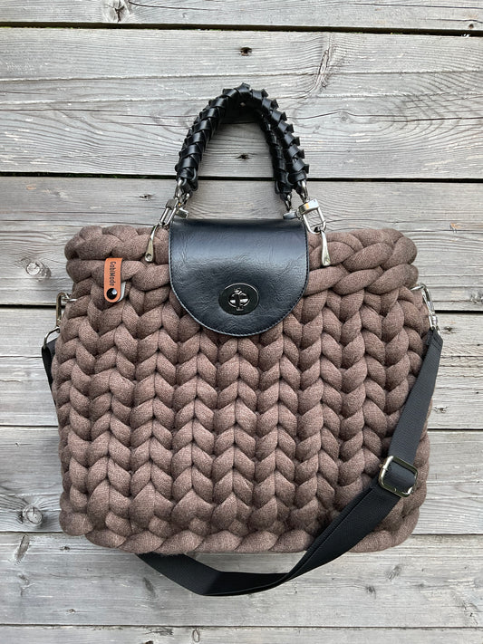 Eine braune gestrickte Tasche mit Griffen und Gurt