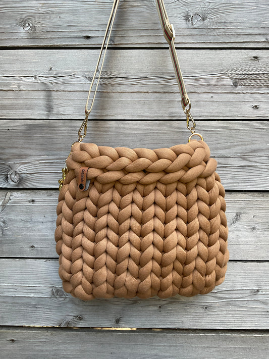 Eine gestrickte Crossbody Tasche in Cognac mit Gurt und kleinem Anhänger