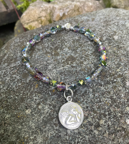 Ein Armband aus schimmernden Perlen und einem Schutzengel Anhänger 