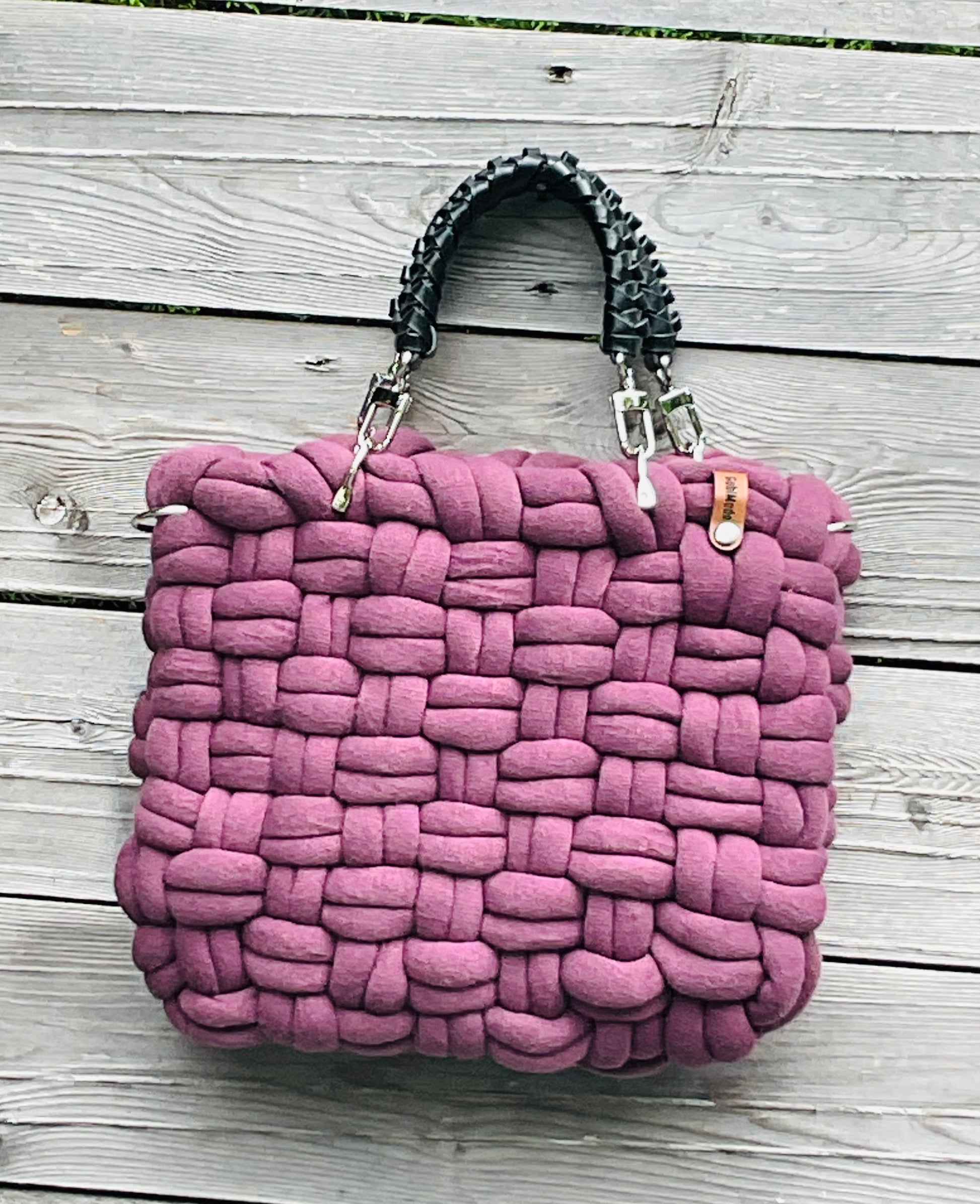 Eine geflochtene Tasche in Plum mit schwarzen Ledergriffen 