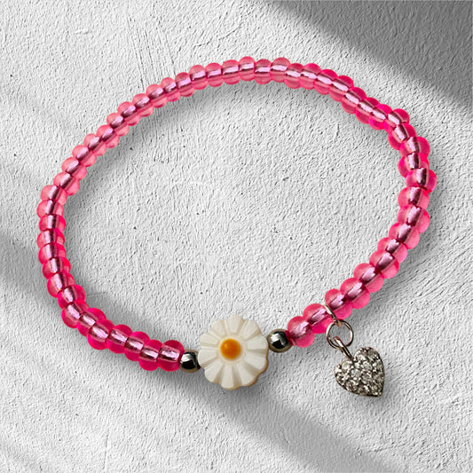 Ein pinkes Armband mit Blumenperle und Herzanhänger 