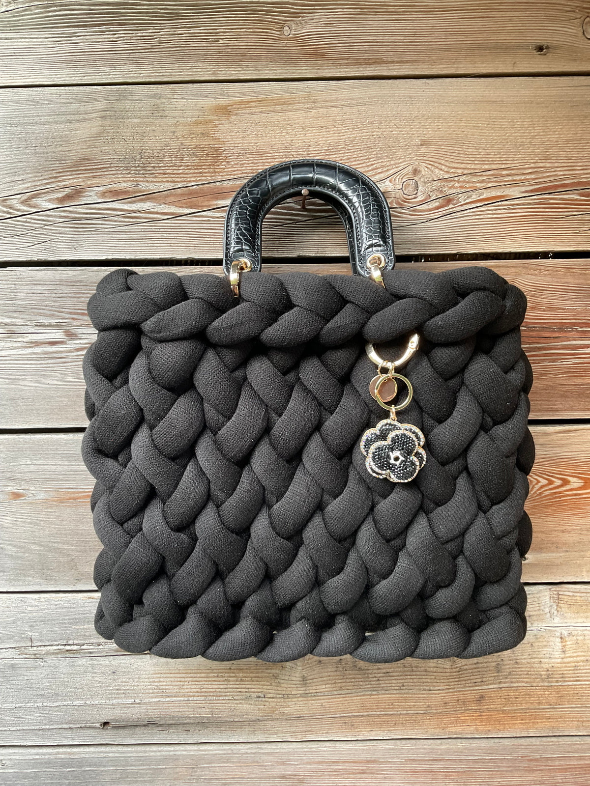 Eine gestrickte schwarze Tasche mit Henkeln und Anhänger 