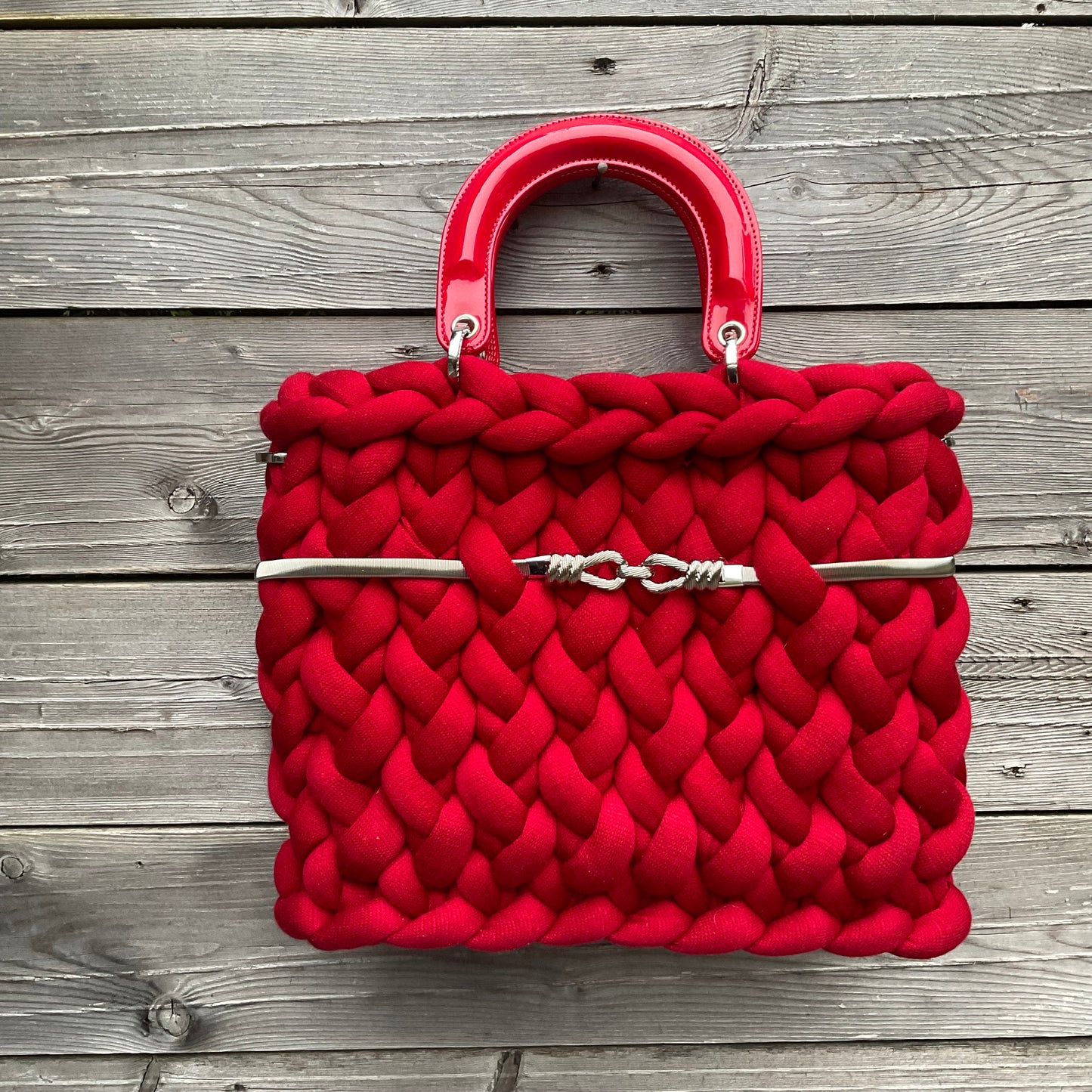 Eine gestrickte rote Tasche mit Gurt und Henkeln 