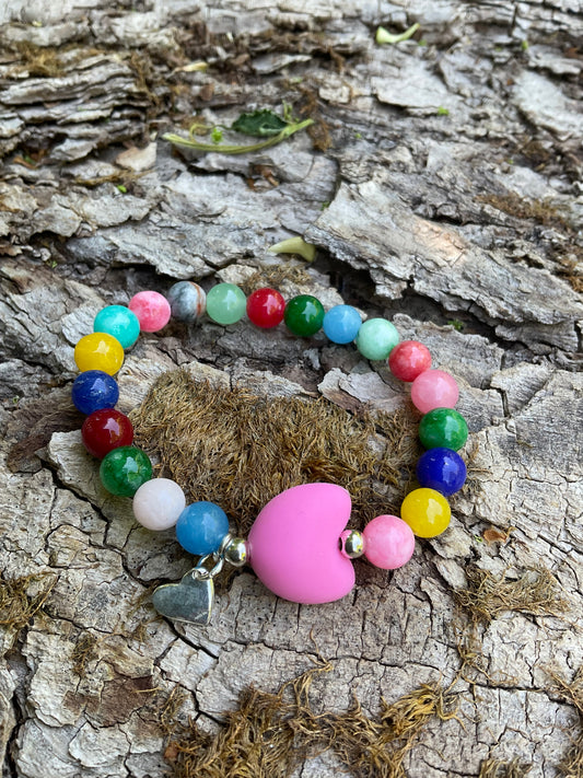 Ein buntes Perlenarmband mir einerm rosa Silikonherz und einem Herzanhänger.