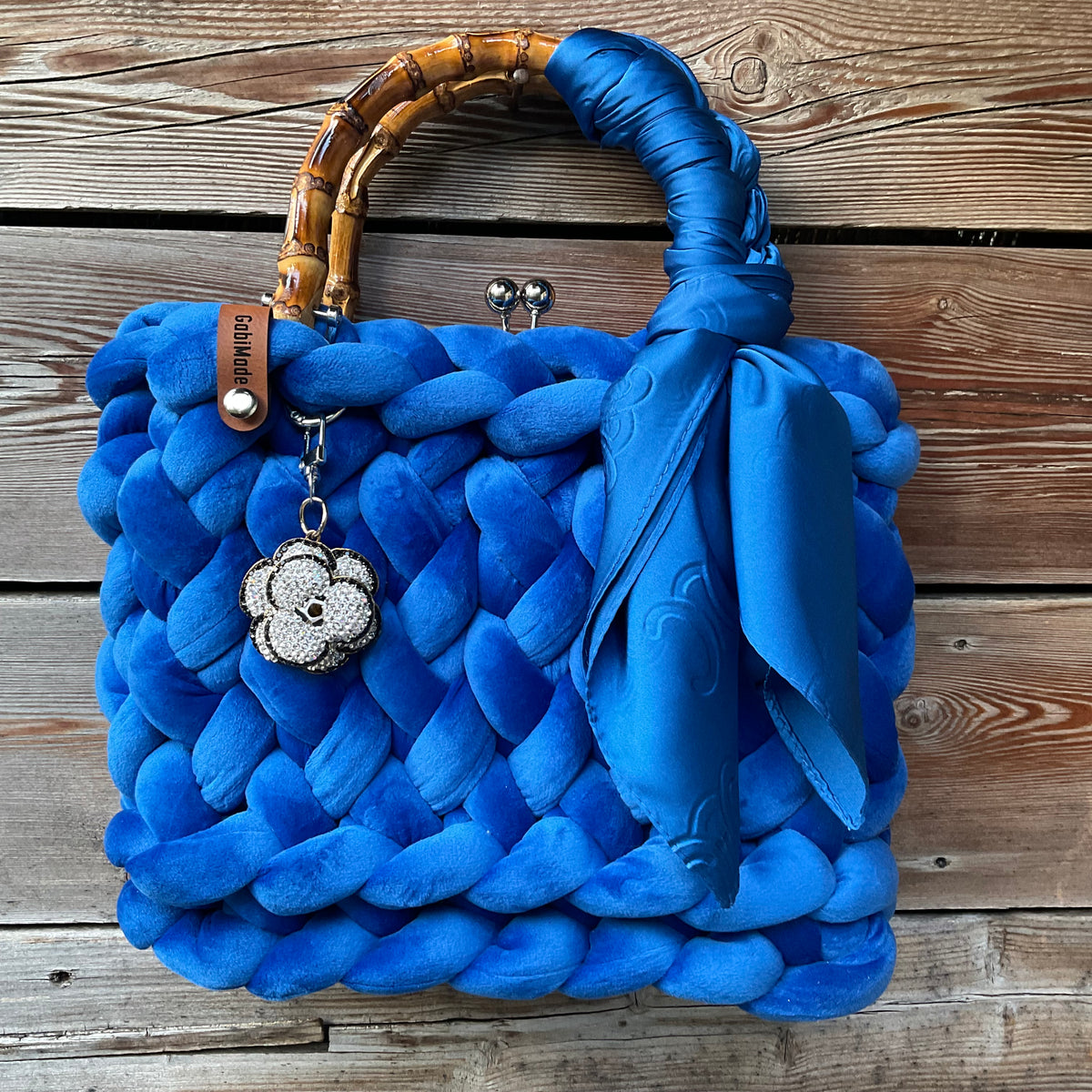 Eine gestrickte blaue amttasche mit Anhänger und Bambusgriffen 