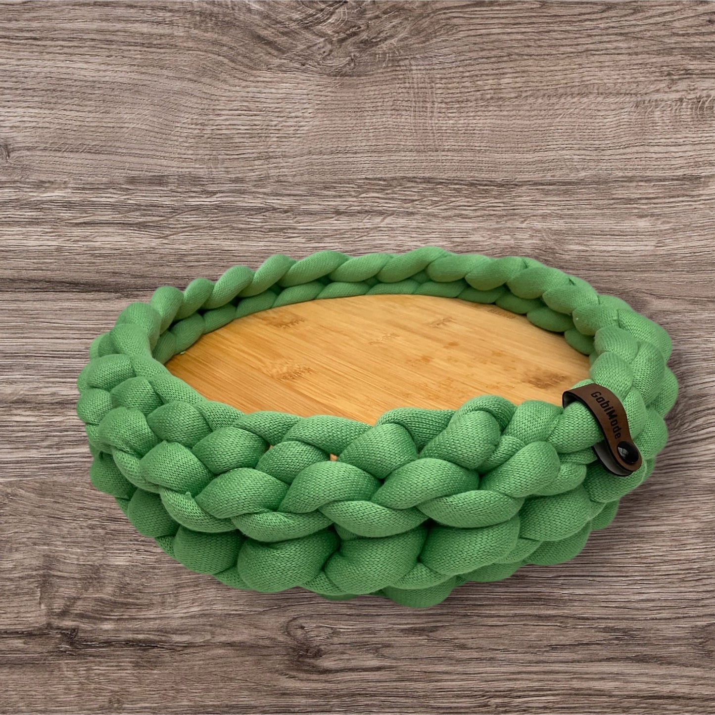 Ein gestricktes grünes Tablett mit Holzteller 