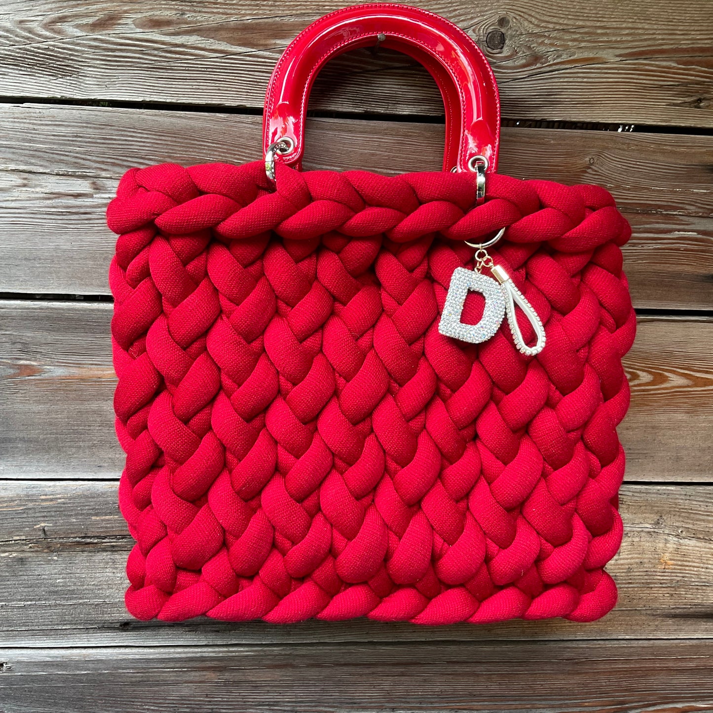 Eine rte gestrickte Tasche mit Henkeln und Anhänger 