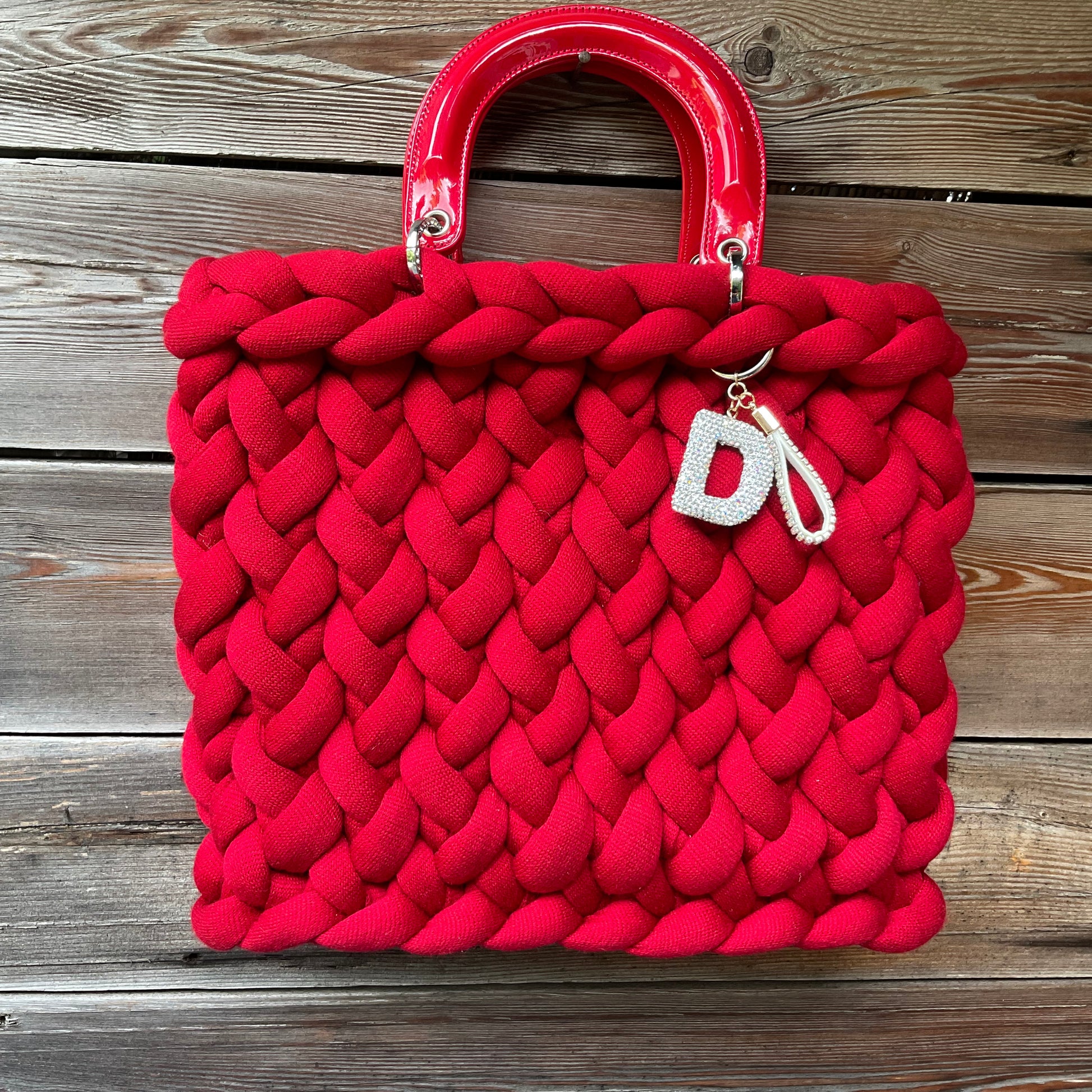 Eine rte gestrickte Tasche mit Henkeln und Anhänger 