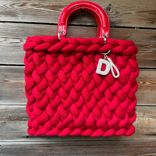 Eine rte gestrickte Tasche mit Henkeln und Anhänger 