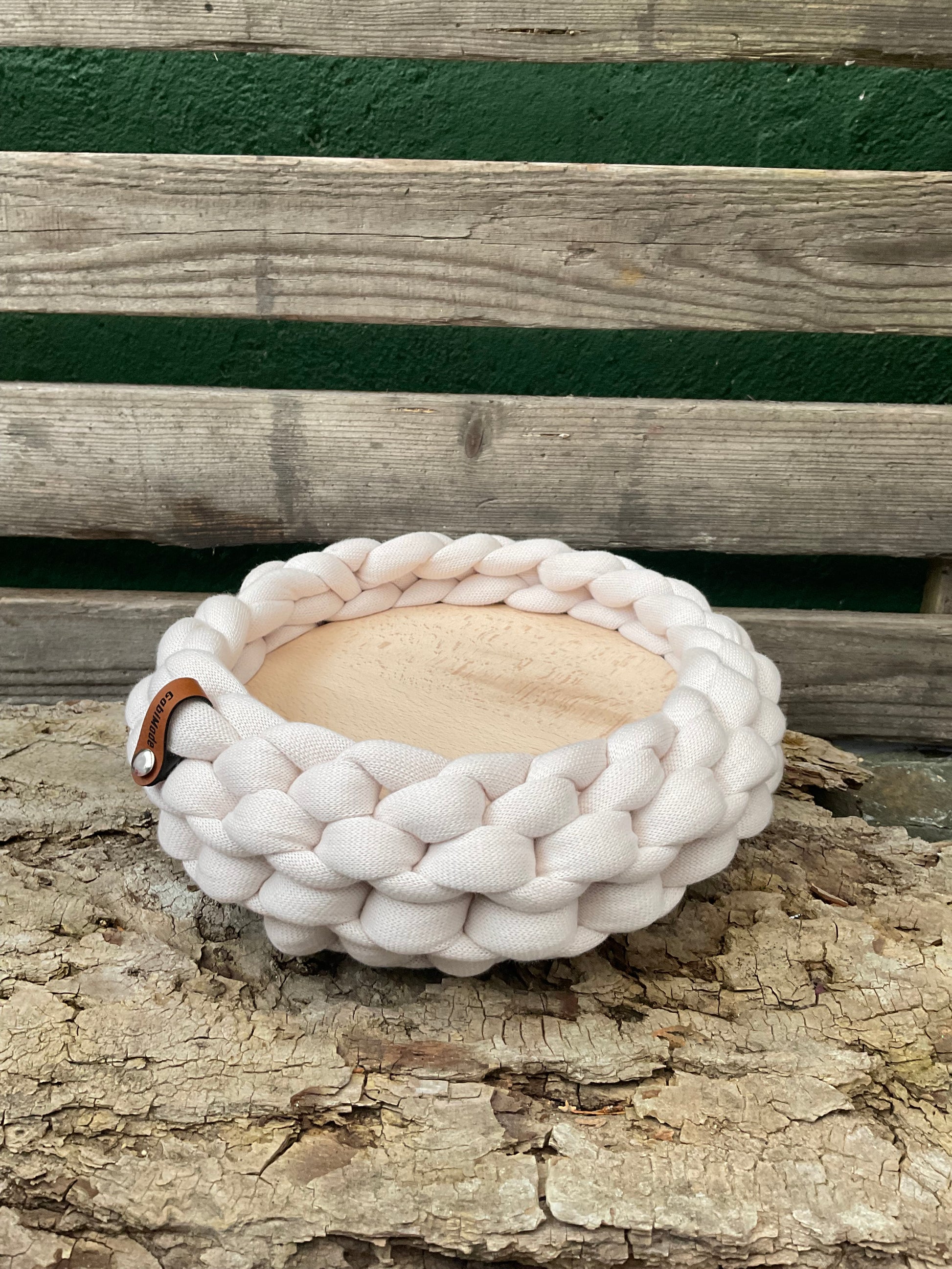 Ein gestricktes Tablett in hellem Beige mit Holzteller 