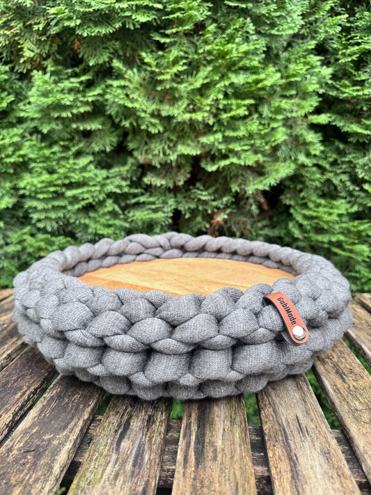 Ein gestricktes graues Tablett mit Holzbrett 