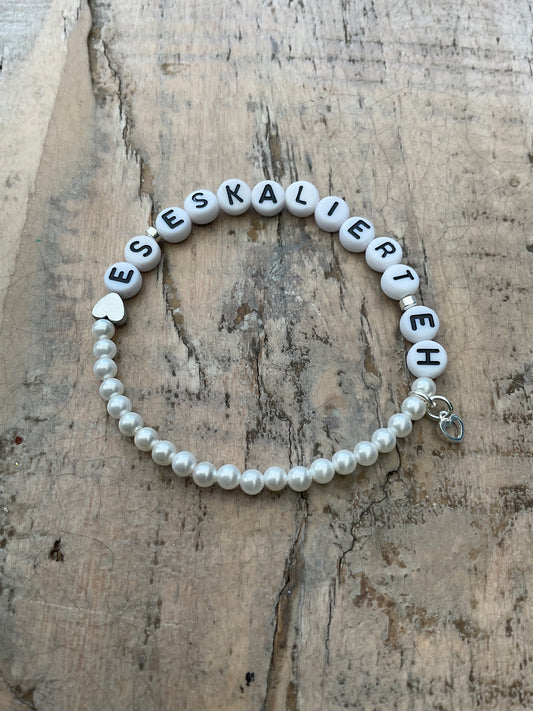 Ein Perlenarmband mit Schrift und Herzanhänger 